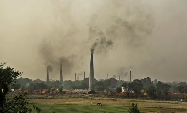 Smoke rises from chimneys of brick kilns on the outskirts of New Delhi, India, Tuesday, June 16, 2015. Never mind lowering the rate of death from air pollution in India and China. Just keeping those rates steady will demand urgent action to clear the skies, according to a new report published Tuesday. (AP Photo/Altaf Qadri)
