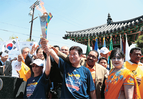 The Special Olympics torch run passed through Koreatown in Los Angeles Thursday. Retired policeman Park Noh-hyun, center, and Los Angeles City Council President Herb Wesson, third from right, were among those who came out for a cultural celebration in front of Da Wool Jung. (Choi Kyung-geun/Korea Times)
