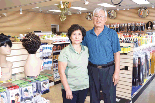 Teresa Kim, left, with husband Gyun-tae Kim stand inside their newly reopened beauty supply store in Baltimore.