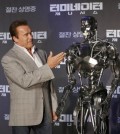 Actor Arnold Schwarzenegger stands with a model of a "Terminator" from the new film "Terminator Genisys" during a press conference at the Ritz Carlton hotel in Seoul, South Korea, Thursday, July 2, 2015. (AP Photo/Ahn Young-joon)
