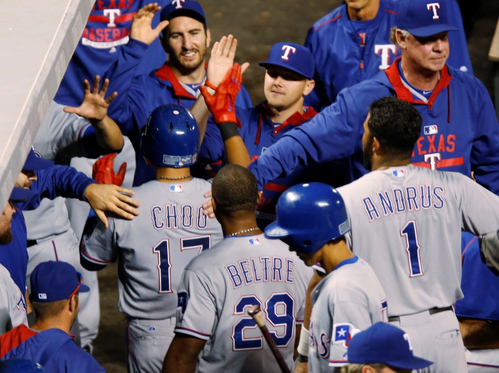 Texas Rangers' Shin-Soo Choo, center left, is congratulated by teammates after he scored on single by Robinson Chirinos during the ninth inning of a baseball game against the Colorado Rockies Tuesday, July 21, 2015, in Denver. Choo tripled in his at-bat to lead off the inning to complete the cycle. (AP Photo/David Zalubowski)