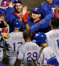 Texas Rangers' Shin-Soo Choo, center left, is congratulated by teammates after he scored on single by Robinson Chirinos during the ninth inning of a baseball game against the Colorado Rockies Tuesday, July 21, 2015, in Denver. Choo tripled in his at-bat to lead off the inning to complete the cycle. (AP Photo/David Zalubowski)