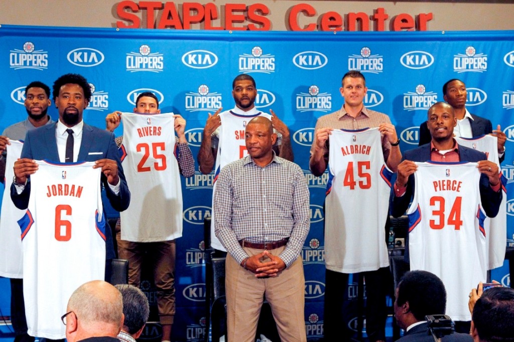 Los Angeles Clippers, head coach Doc Rivers, center, poses team players, from left, Branden Dawson, 22, DeAndre Jordan, 6, Austin Rivers, 25, Josh Smith, 5, Cole Aldrich, 45, Paul Pierce, 34, and Wesley Johnson, 33, far right, at at a news conference in Los Angeles on Tuesday, July 21, 2015. The Clippers managed to keep DeAndre Jordan after he changed his mind about his verbal commitment to Dallas Mavericks. They offered everything he wanted, including a fresh start and a bigger offensive role. When Jordan thought about it a little more, the craziest free-agent recruitment story in recent NBA history ended with him back on the Los Angeles Clippers. (AP Photo/Nick Ut)