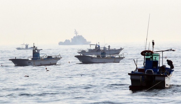 Guarded by South Korean naval ships, fishing boats operate. (Yonhap)