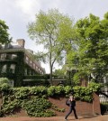 A woman walks by buildings on the campus of Harvard University in Cambridge, Mass. (AP Photo/Elise Amendola)