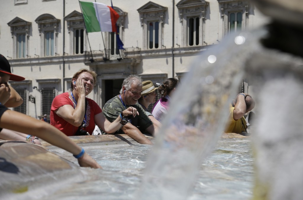 People cool off in a public fountain past Rome's Palazzo Chigi government office, Monday, July 20, 2015. Temperatures in Rome this week could hit 38-39C (100-102F): sizzling heat and oppressive humidity have gripped Italy this month, with some nights in Rome seeing "low" temperatures hovering near 30C (86F). (AP Photo/Gregorio Borgia)