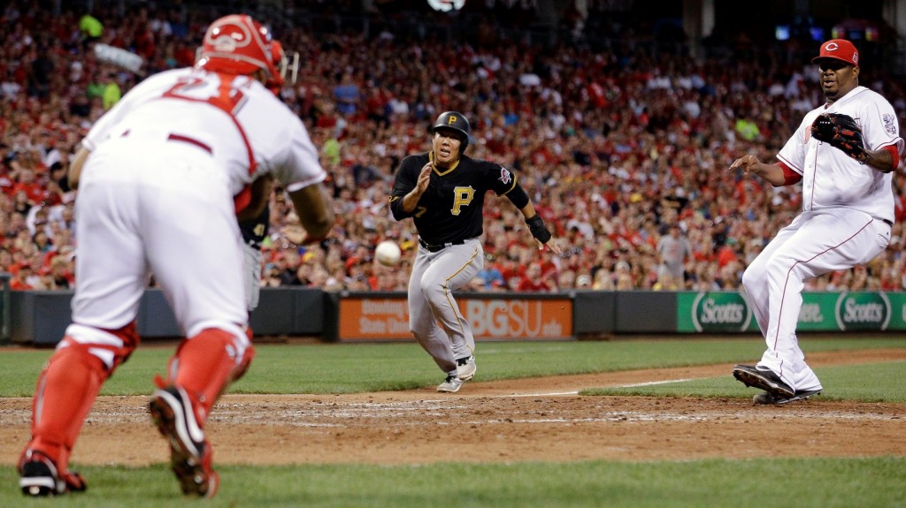 Pittsburgh Pirates' Kang Jung Ho runs home to score against Cincinnati Reds catcher Brayan Pena, left, and relief pitcher Jumbo Diaz, right, on a wild pitch by diaz in the sixth inning of a baseball game, Friday, July 31, 2015, in Cincinnati. (AP Photo/John Minchillo)