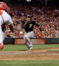 Pittsburgh Pirates' Kang Jung Ho runs home to score against Cincinnati Reds catcher Brayan Pena, left, and relief pitcher Jumbo Diaz, right, on a wild pitch by diaz in the sixth inning of a baseball game, Friday, July 31, 2015, in Cincinnati. (AP Photo/John Minchillo)