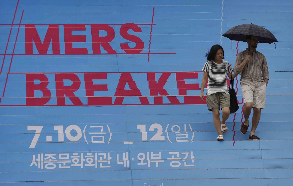 A couple passes by letters on the stairs to advertise a festival called "MERS(Middle East Respiratory Syndrome) Breaker" to hope an end to the MERS outbreak at the Sejong Culture Center in Seoul, South Korea, Sunday, July 12, 2015. South Korean letters read " The Sejong Culture Center. " (AP Photo/Ahn Young-joon)