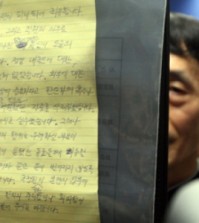 An official at Yongin Dongbu Police Station in Yongin, South Korea, on July 19, 2015, holds up a page of the will left by a National Intellgence Service employee who was found dead the previous day. (Yonhap)