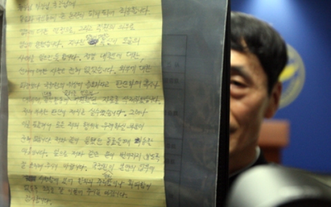 An official at Yongin Dongbu Police Station in Yongin, South Korea, on July 19, 2015, holds up a page of the will left by a National Intellgence Service employee who was found dead the previous day. (Yonhap)