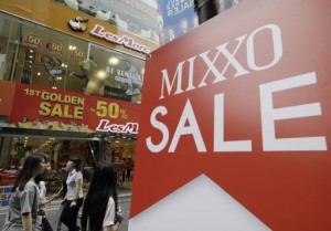 People walk past sale signs at a Seoul shopping district, South Korea, Thursday, July 23, 2015. South Korea's quarterly growth slowed to the lowest in more than two years as a severe drought hit agriculture and an outbreak of Middle East respiratory syndrome sapped consumption.(AP Photo/Ahn Young-joon)