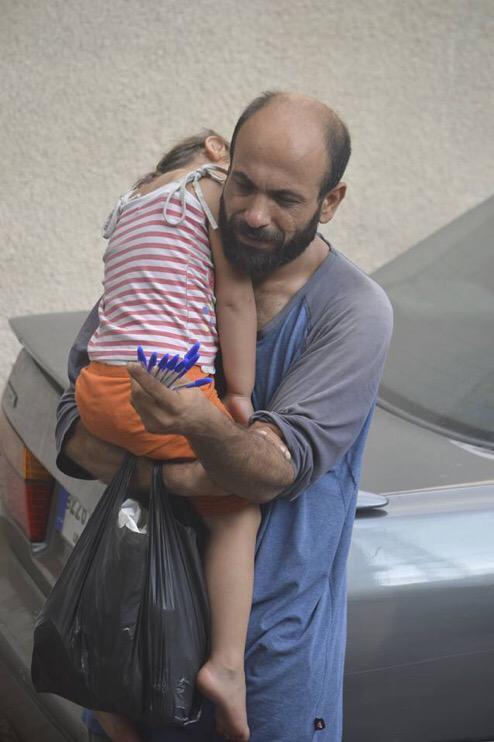 Single father and Syrian refugee Abdul holds his sleeping daughter while trying to sell pens in the streets of Beirut. (Twitter)