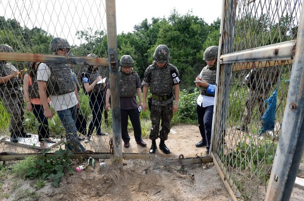 In this Aug. 9, 2015, photo provided by the Defense Ministry, an unidentified South Korean army official, second from right, gives a briefing to the media at the scene of a blast inside the demilitarized zone in Paju, South Korea. Vowing to hit back, South Korea said Monday, Aug. 10, 2015, that North Korean soldiers laid the three mines that exploded last week at the border and maimed two South Korean soldiers. (The Defense Ministry via AP)