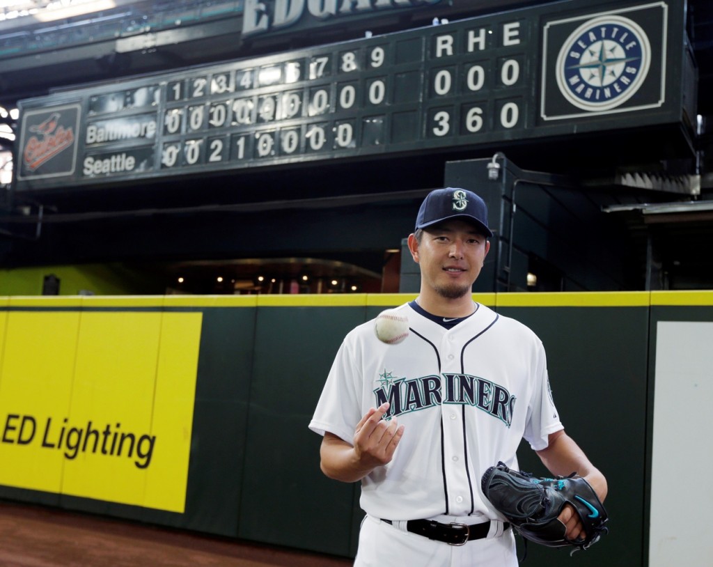 Seattle Mariners starting pitcher Hisashi Iwakuma tosses a baseball as he poses for a photo in front of the manual scoreboard at Safeco Field after he threw a no-hitter against the Baltimore Orioles in a baseball game Wednesday, Aug. 12, 2015, in Seattle. The Mariners won 3-0. (AP Photo/Ted S.)