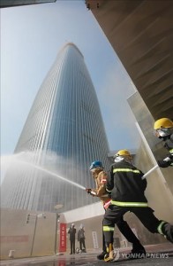 In the file photo taken on April 23, 2015, firefighters spray water in front of Lotte World Tower, a 123-story skyscraper, in Seoul's Songpa Ward, as they conduct a firefighting drill. Prosecutors said on Aug. 10, 2015, they have indicted Lotte Engineering & Construction Co. over poor construction management of the building. (Yonhap)