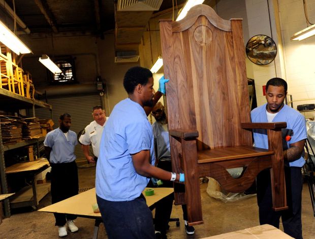 Inmates Rameen Perrin, left, and Evan Davis working a chair carved out of walnut for Pope Francis to use during his planned visit to the prison next month, Monday, Aug. 24, 2015, at the Curran-Fromhold Correctional Facility in Philadelphia. Francis plans to meet on Sept. 27 with about 100 inmates and some of their relatives during a two-day trip to the city. (AP Photo/Michael Perez)