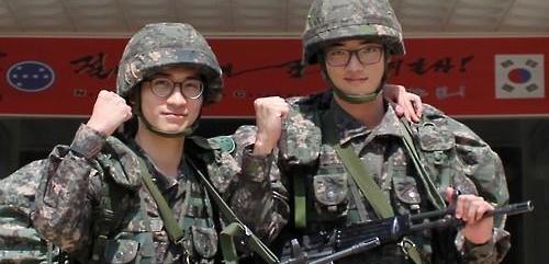 This undated photo, released on Aug. 24, 2015, by the Army headquarters, shows two South Korean soldiers, Sgt. Chun Moon-kyun (L) and Sgt. Joo Chan-joon, posing for a photo. The two, from the 7th Division, have decided to have their discharge from the Army postponed at a time when tensions between the Koreas have risen dramatically after South Korea accused North Korea of orchestrating a land mine attack that maimed two South Korean soldiers. The North also fired artillery shells across the border on Aug. 20, prompting South Korea to fire back dozens of shells. (Yonhap)