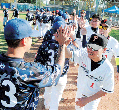 A player from South Korea's Gyeonggi Provincial Police Agency's baseball team high fives another policeman at the LAPD's Wild Wild West Invitational Tuesday. (Park Sang-hyuk/Korea Times)