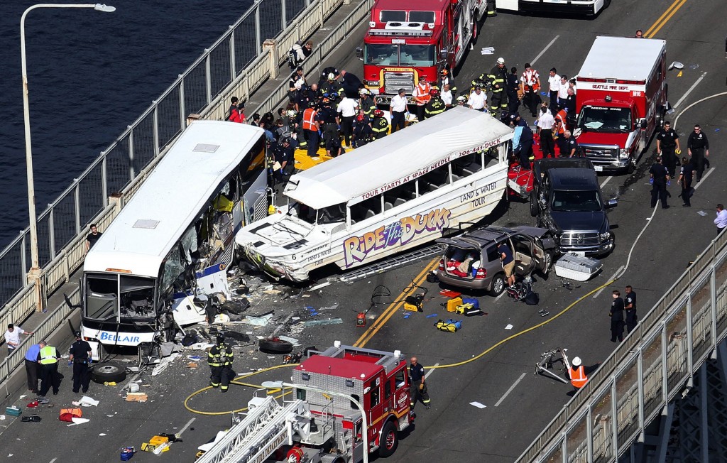 Emergency personnel work at the scene of a fatal collision involving a charter bus, center left, and a "Ride the Ducks" amphibious tour bus on the Aurora Bridge in Seattle on Thursday, Sept. 24, 2015. (Ken Lambert/The Seattle Times via AP) 