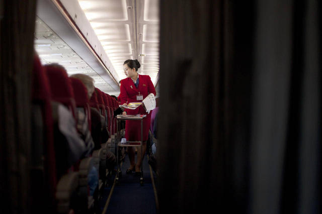 An Air Koryo attendant offers North Korean newspapers and magazines before take off for Pyongyang on April 11, 2013.  (Alexander F. Yuan/AP Photo)