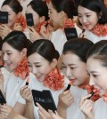 A group of newly-hired flight attendants puts on lipstick during a makeup training session at an office of Jeju Air Co., South Korea's top budget carrier, in Seoul on Sept. 9, 2015. The session is part of a training program that new employees are required to go through. (Yonhap)