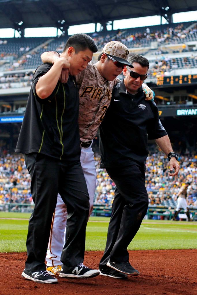 Pittsburgh Pirates' Jung Ho Kang, center, is helped off the field by a team trainer, right, and his interpreter after injuring his left leg turning a double play in the first inning of a baseball game against the Chicago Cubs in Pittsburgh, Thursday, Sept. 17, 2015. Kang left the game. (AP Photo/Gene J. Puskar)