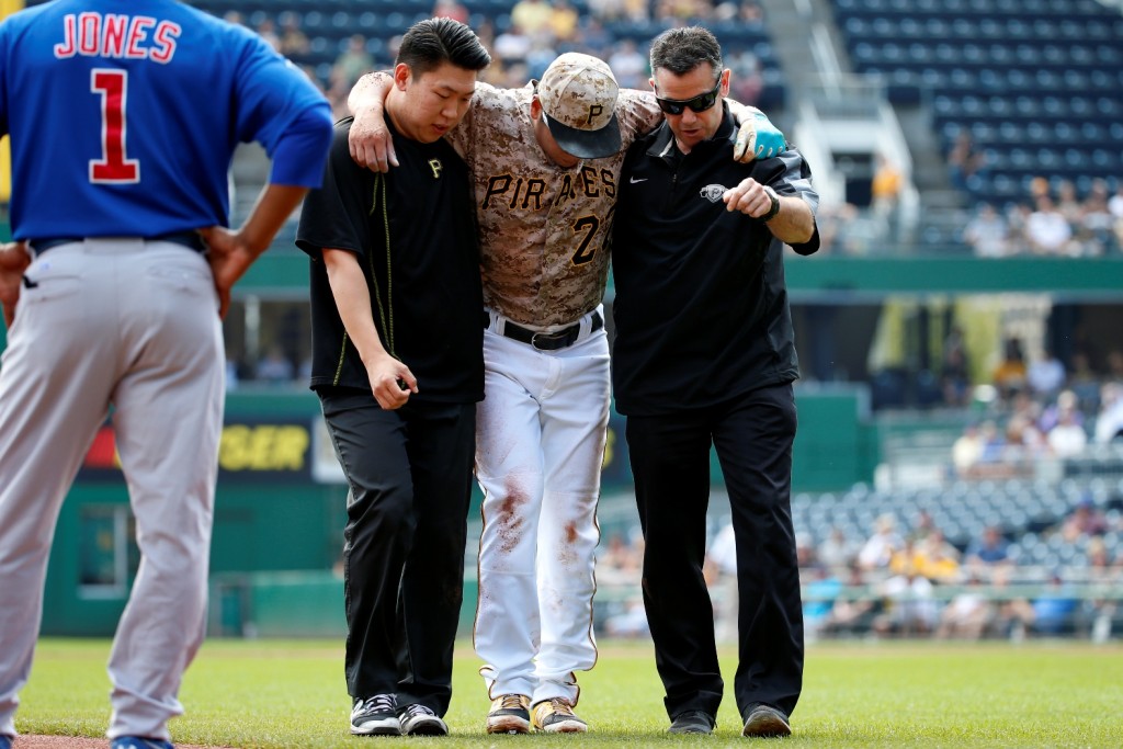 Pittsburgh Pirates' Kang Jung-ho, center, is helped off the field by a team trainer, right, and his interpreter after injuring his left leg turning a double play in the first inning of a baseball game against the Chicago Cubs in Pittsburgh, Thursday, Sept. 17, 2015. Kang left the game. (AP Photo/Gene J. Puskar)