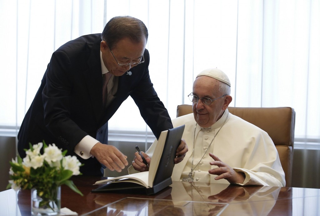 Pope Francis, right, finishes signing a guest book as United Nations Secretary Ban Ki-moon helps him close the book  at the United Nations headquarters, Friday, Sept. 25, 2015. (Joshua Lott/Pool Photo via AP)