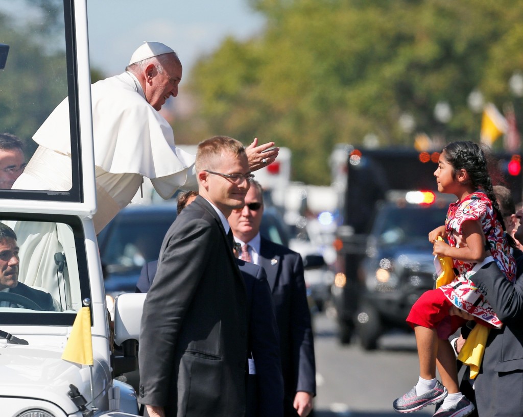 Pope Francis reaches for a child from the popemobile that was brought to him, during a parade in Washington, Wednesday, Sept. 23, 2015, following a state arrival ceremony hosted by President Barack Obama at the White House. (AP Photo/Alex Brandon, Pool)