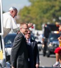 Pope Francis reaches for a child from the popemobile that was brought to him, during a parade in Washington, Wednesday, Sept. 23, 2015, following a state arrival ceremony hosted by President Barack Obama at the White House. (AP Photo/Alex Brandon, Pool)