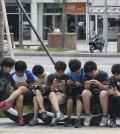 South Korean high school students play games on their smartphones on a bench on the sidewalk in Seoul, South Korea. Security researchers say they found critical weaknesses in a South Korean government-mandated child surveillance app, vulnerabilities that could have allowed hackers to easily violate the private lives of the country’s youngest citizens. (AP Photo/Ahn Young-joon, File)