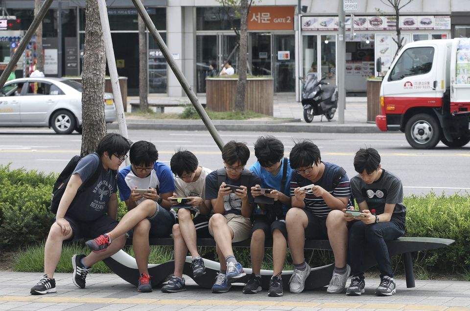 South Korean high school students play games on their smartphones on a bench on the sidewalk in Seoul, South Korea. Security researchers say they found critical weaknesses in a South Korean government-mandated child surveillance app, vulnerabilities that could have allowed hackers to easily violate the private lives of the country’s youngest citizens. (AP Photo/Ahn Young-joon, File)