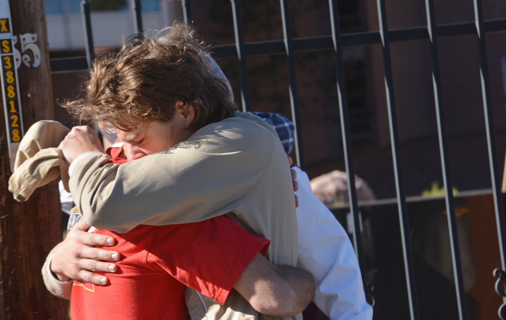 Two people embrace outside a Northern Arizona University student dormitory, Friday, Oct. 9, 2015, in Flagstaff, Ariz., after an early morning confrontation between two groups of students escalated into gunfire. (AP Photo/Josh Biggs)