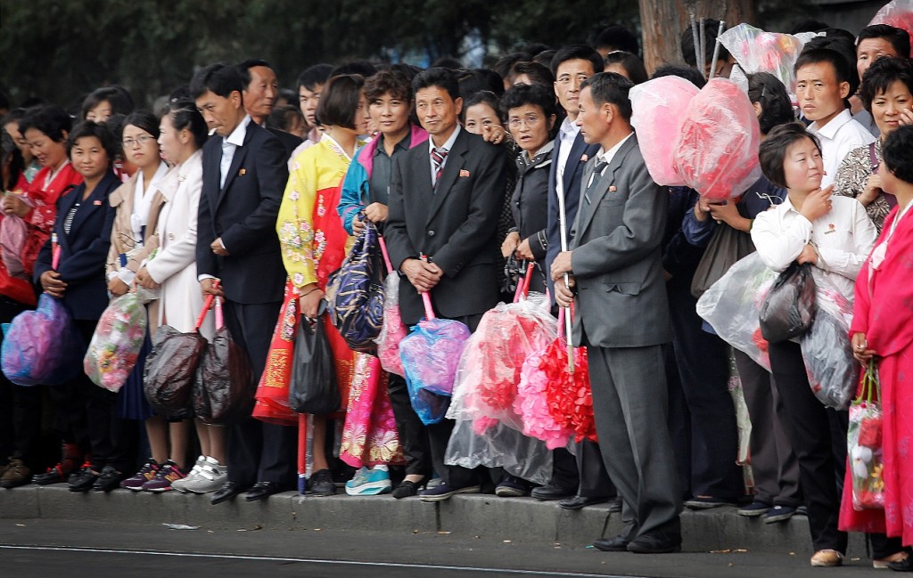 North Koreans carry decorative flowers to be used during upcoming anniversary celebrations while waiting at a city trolley stop, Thursday, Oct. 8, 2015, in Pyongyang, North Korea. The country is in high gear with preparations for the 70th anniversary of the founding of North Korea's Workers' Party on Oct. 10, 2015. (AP Photo/Wong Maye-E)