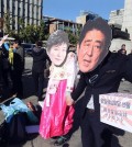 Protesters wearing masks of Japanese Prime Minister Shinzo Abe, right, and South Korean President Park Geun-hye prepare to join in a rally against Abe's planned visit in Seoul, South Korea, Friday, Oct. 30, 2015. Abe and Chinese Premier Li Keqiang will visit Seoul for their trilateral summit with Park. (AP Photo/Ahn Young-joon)