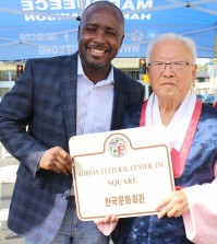 Lee Gwang-deok, president of the Korean Cultural Center, and Los Angeles City Councilman Marqueece Harris-Dawson hold up a sign designating the Korean Cultural Center Inc. Square. (Bae Goon-chan/Korea Times)