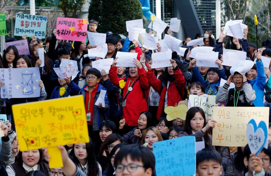 South Korean students hold signs during a rally demanding full compensation and apology for wartime sex slaves from Japanese government near the Japanese Embassy in Seoul, South Korea, Wednesday, Oct. 28, 2015. Only days before leaders from South Korea, Japan and China are to gather in Seoul this weekend, the event has still not yet been formally settled, with the South Korean and Japanese foreign ministries publicly dodging questions even as diplomats leak barbed tidbits to reporters behind the scenes. The problem this week, as is often the case in Northeast Asia, appears to be history, and specifically the inability of Seoul and Tokyo to settle disputes stemming from Japan’s brutal colonial rule of Korea in the early 20th century. The letters read "Apology and Live long and stay healthy." (AP Photo/Lee Jin-man)
