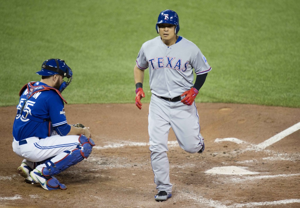 Texas Rangers' Choo Shin-soo, right, crosses home plate in front of Toronto Blue Jays catcher Russell Martin following a solo home run during the third inning in Game 5 of baseball's American League Division Series, Wednesday, Oct. 14, 2015 in Toronto. (Darren Calabrese/The Canadian Press via AP)