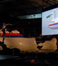 A video show the impact of a missile on Malaysia Airline Flight 17, while a part of the reconstructed forward section of the fuselage is displayed behind, as Tjibbe Joustra, left, head of the Dutch Safety Board presents the board’s final report into what caused Malaysia Airlines Flight 17 to break up high over Eastern Ukraine last year, killing all 298 people on board, during a press conference in Gilze-Rijen, central Netherlands, Tuesday, Oct. 13, 2015. (AP Photo/Peter Dejong)