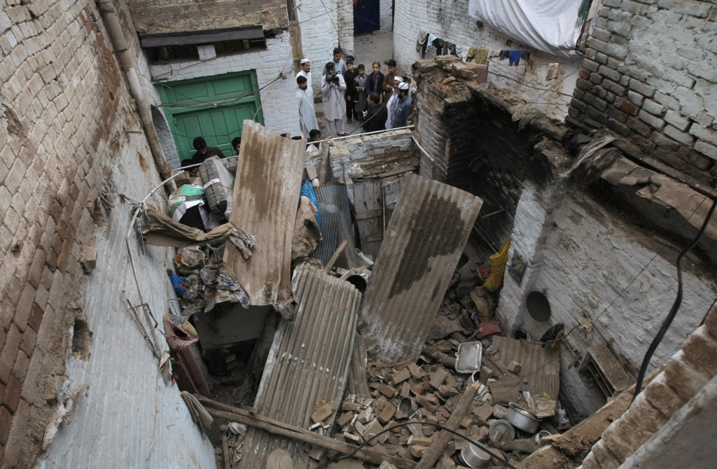 People stand outside a house damaged from an earthquake in Peshawar, Pakistan, Monday, Oct. 26, 2015. A powerful 7.7-magnitude earthquake in northern Afghanistan rocked cities across South Asia. Strong tremors were felt in Kabul, New Delhi and Islamabad on Monday. In the Pakistani capital, walls swayed back and forth and people poured out of office buildings in a panic, reciting verses from the Quran. (AP Photo/Mohammad Sajjad)