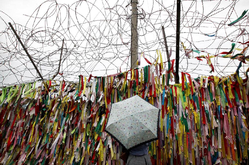 A visitor reads messages on ribbons wishing for the reunification of the two Koreas at the Imjingak Pavilion near the border village of Panmunjom, which has separated the two Koreas since the Korean War, in Paju, South Korea, Tuesday, Aug. 25, 2015. After more than 40 hours of talks, North and South Korea pulled back from the brink Tuesday with an accord that allows both sides to save face and, for the moment, avert the bloodshed they've been threatening each other with for weeks.(AP Photo/Ahn Young-joon)