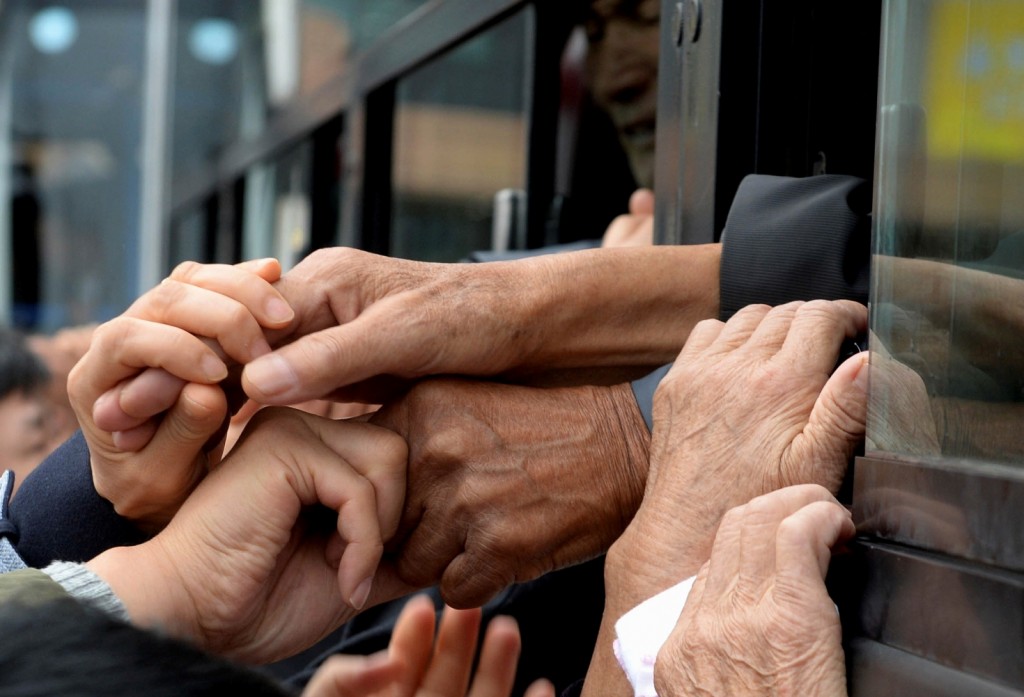 South Koreans and their North Korean relatives on a bus grip their hands each other to bid farewell after the Separated Family Reunion Meeting at Diamond Mountain resort in North Korea, Thursday, Oct. 22, 2015. Hundreds of elderly Koreans are weeping and embracing as they part — perhaps for good — after briefly reuniting for the first time in more than 60 years. About 390 South Koreans traveled to the North's scenic Diamond mountain resort earlier this week to meet for three days with relatives they were separated from during the turmoil of the 1950-53 Korean War. (Korea Pool Photo via AP) 