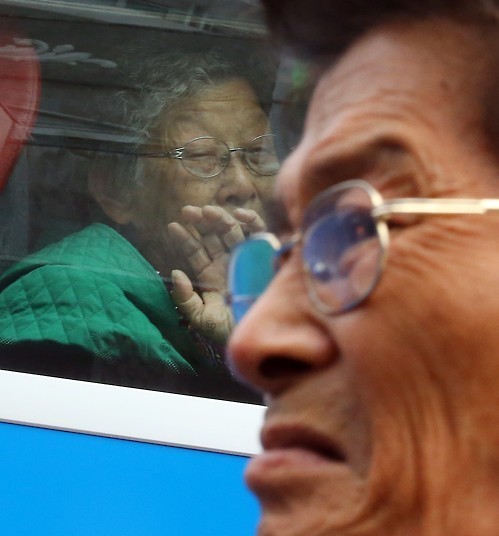 Jung Gun-mok, front, a 64-year-old former South Korean fisherman who was abducted by North Korea in the Yellow Sea about 40 years ago, looks away as he is about to burst into tears, as he bids farewell to his mother on the bus. His mother Lee Bok-soon, 88, helplessly looks out the window as the bus is about to leave the resort on Mount Kumgang on the North's east coast on Oct. 26, 2015, the last day of the three-day reunions.  (Yonhap)
