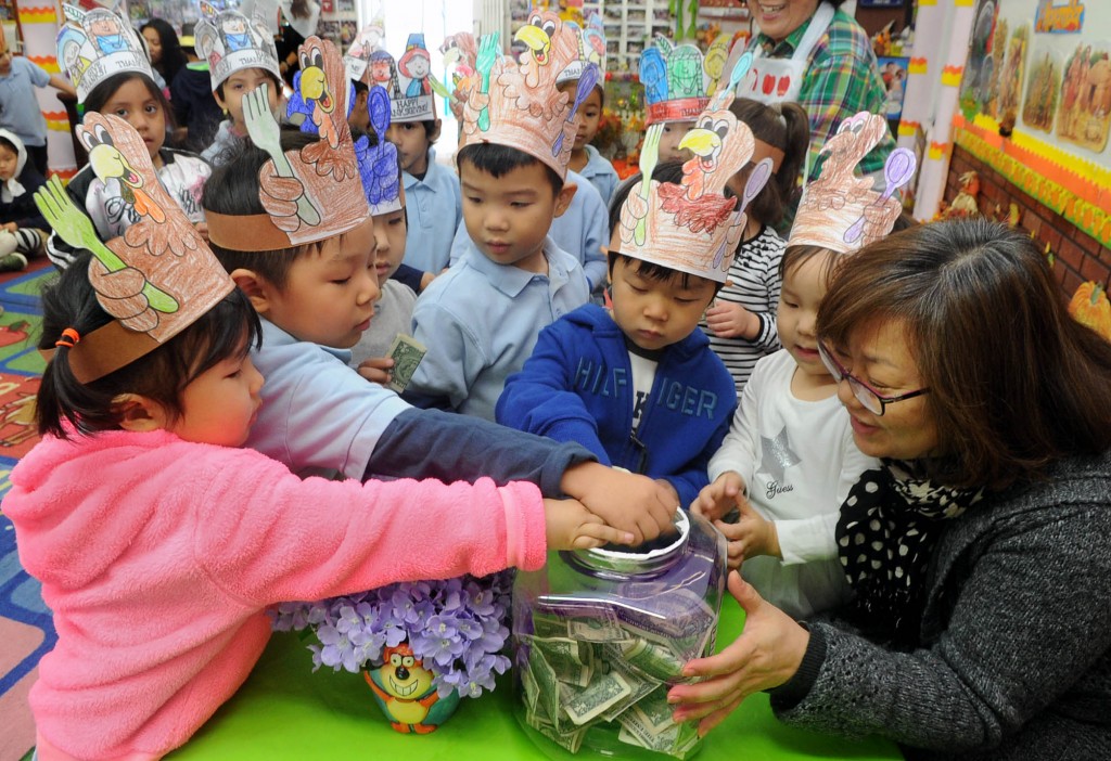 Children wearing turkey hats at Lily Preschool and Kindergarten in Los Angeles put money in a donation jar to help the kids who live on the streets of India. (Park Sang-hyuk)