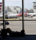 A traveler rests on the floor as American Airlines aircraft are lined up the the gates at Miami International Airport, Tuesday, Nov. 24, 2015, in Miami. Thanksgiving is one of the busiest travel holidays of the year, both in the air and on the roads. (AP Photo/Lynne Sladky)