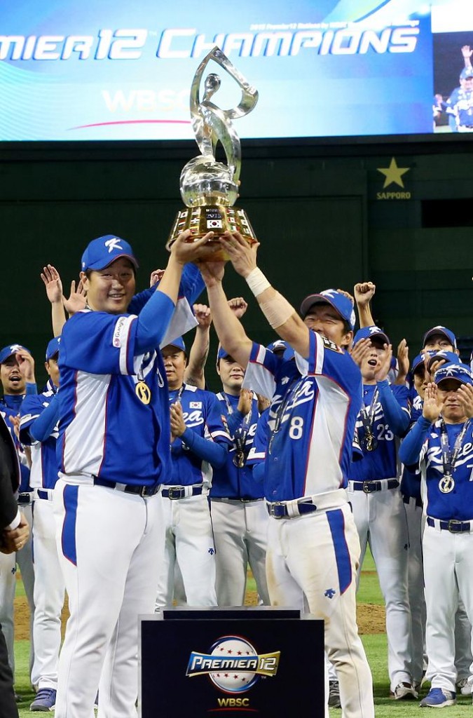 South Korea's Lee Dae-ho (L) and Jeong Keun-woo hold up the trophy as they celebrate after defeating the United States in the final of WBSC Premier 12 baseball tournament at Tokyo Dome in the Japanese capital on Nov. 21, 2015. South Korea won the match 8-0 to become the inaugural champion of the tournament. (Yonhap) 