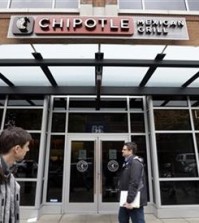 FILE - In this Nov. 9, 2015, file photo, pedestrians walk past a still-closed Chipotle restaurant in Seattle. An outbreak of E. coli that originated in the Pacific Northwest has spread south and east and has now infected people in six states. New cases have been reported in California, New York and Ohio, the Centers for Disease Control and Prevention said Friday, Nov. 20, 2015. (AP Photo/Elaine Thompson, File)