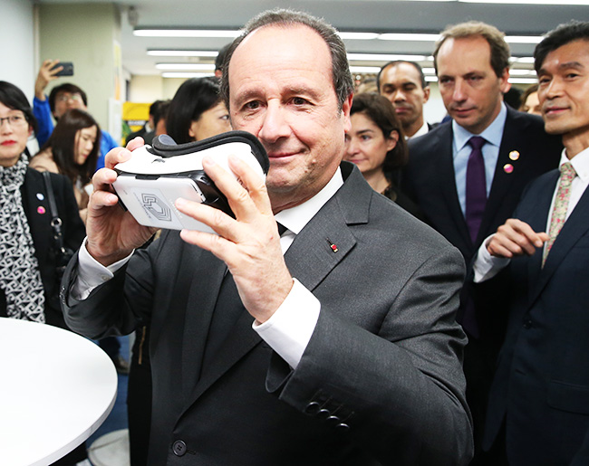 French President in Korea: French President Francois Hollande tries on three-dimensional glasses during a visit to D.CAMP, an organization helping start-up companies, in Seoul, Wednesday. (Yonhap) 