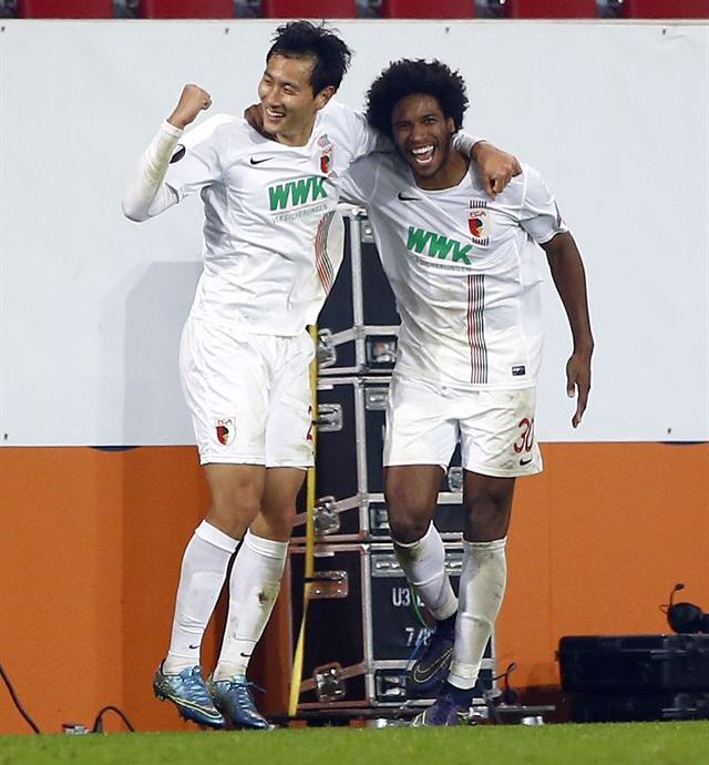 Augsburg's Ji Dong-won, left, celebrates with teammate Caiuby after scoring his side's third goal during the Europa League Group L soccer match between FC Augsburg and AZ Alkmaar at the WWK Arena in Augsburg, southern Germany, Thursday Nov. 5, 2015. (AP Photo/Matthias Schrader)